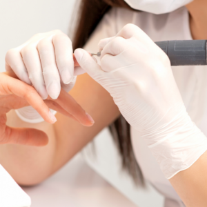 Una especialista removiendo el gel de las uñas a una persona