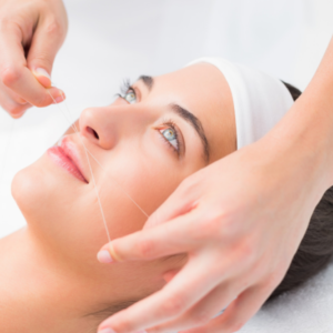 Una mujer recibiendo un tratamiento de depilacion facial con hilos