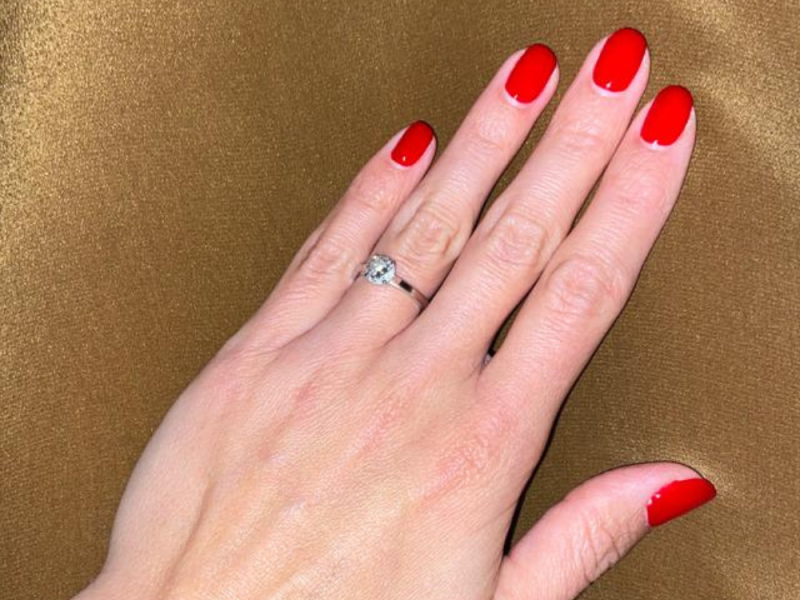 Una mujer mostrando su mano con sus uñas recien pintadas de rojo