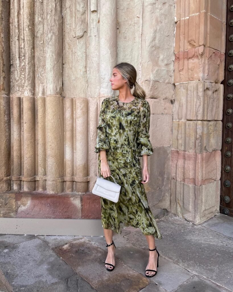 Una mujer posando para una foto usando un elegante vestido y un bolso de alta calidad