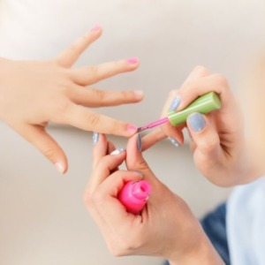 Una especialista aplicando pintura de uñas a una niña cuidadosamente