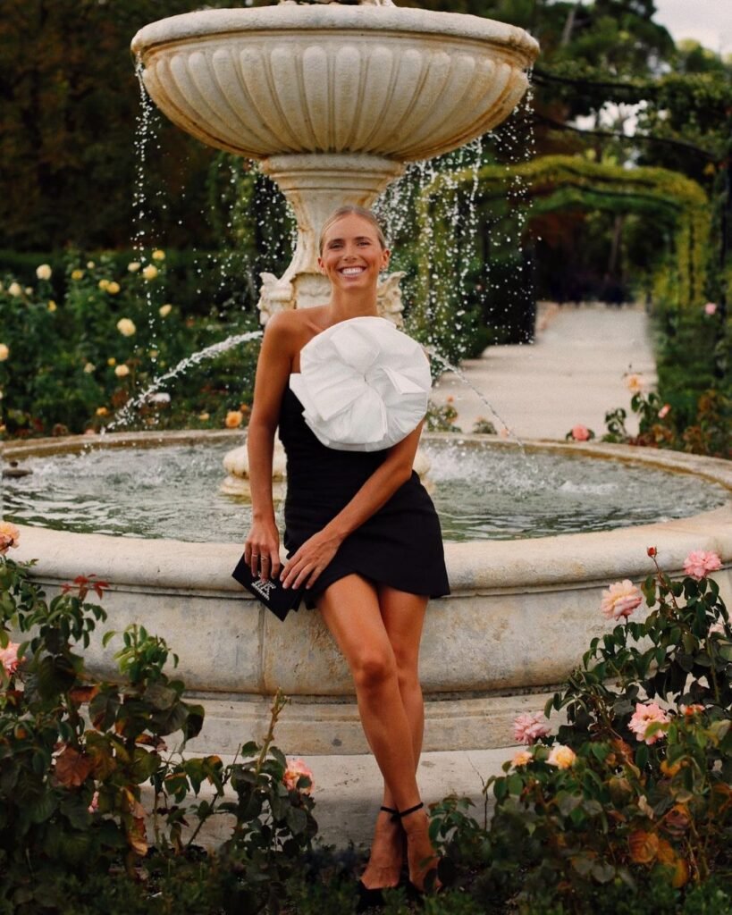 Una mujer alegre posando para una foto mientras esta sentada en la orilla de una fuente