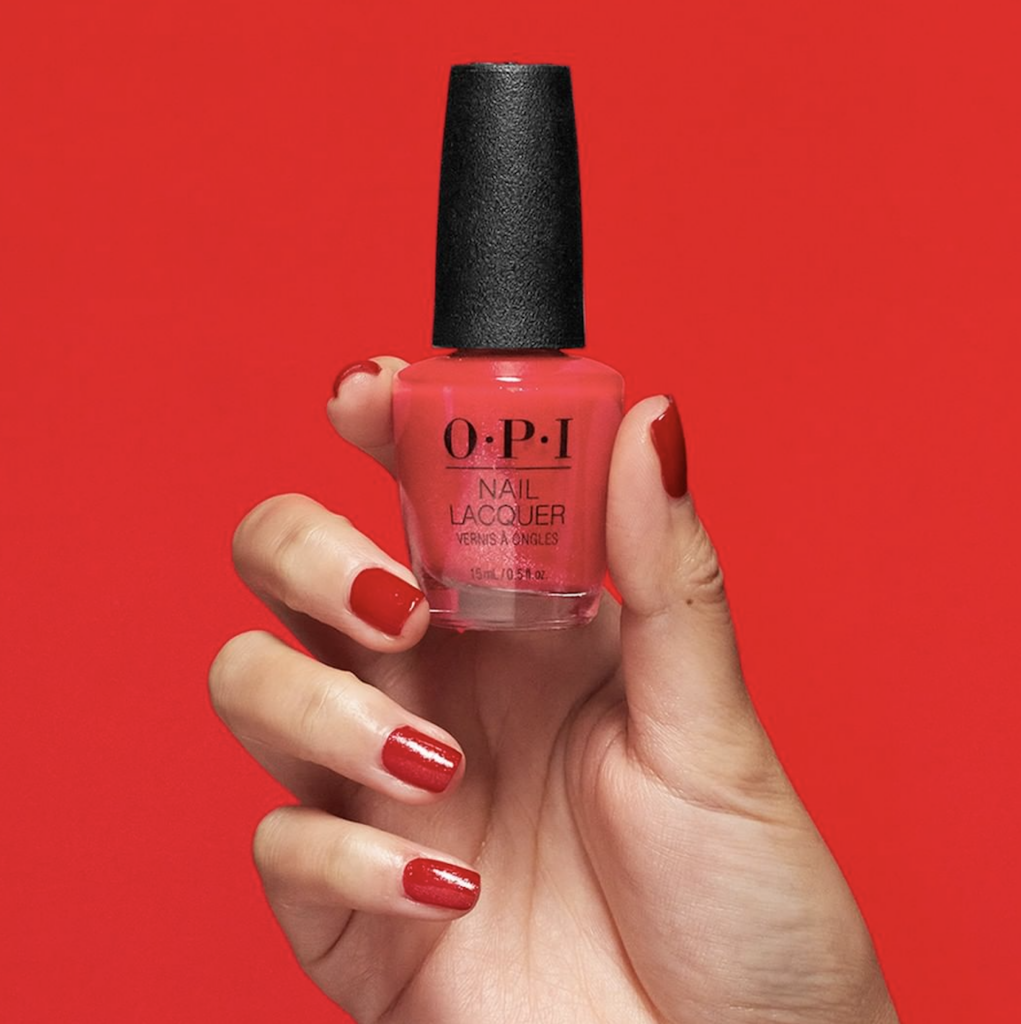 Una persona sosteniendo un frasco de pintura roja para uñas de la firma OPI