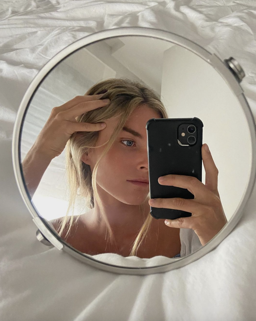 Una mujer sacando posando en el espejo para una selfie