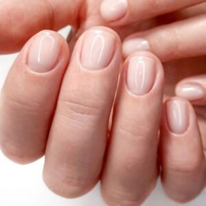 Una mujer mostrando solamente las uñas de sus dedos en la mano izquierda