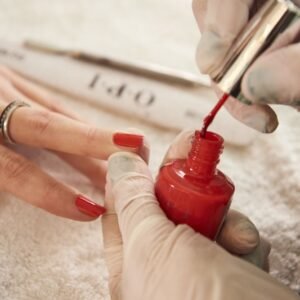 Un especialista aplicando pintura de uñas a una señora