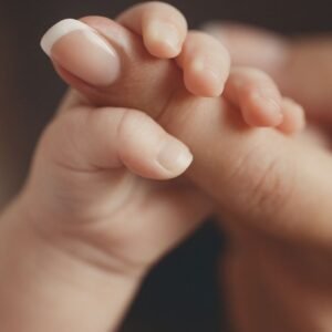 La mano de una bebe sosteniendo el dedo de su madre